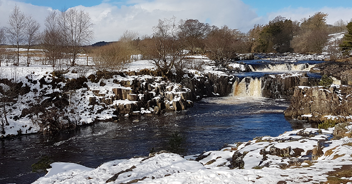 Low Force Waterfall and surrounding countryside covered in snow. 